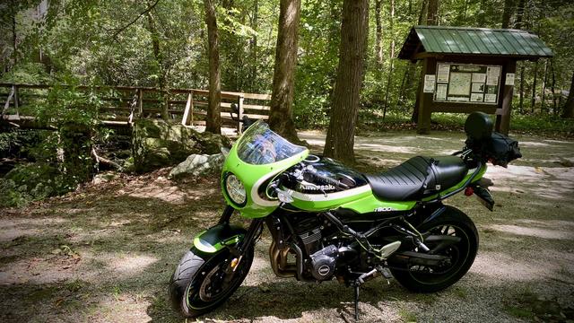 A Kawasaki z900rs-cafe motorcycle in the forest parked in front of a footbridge across Frogtown Creek