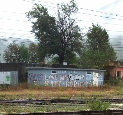 Ein Graffiti entlang der Zugsgleise mit der Aufschrift "Love trains, hate borders"