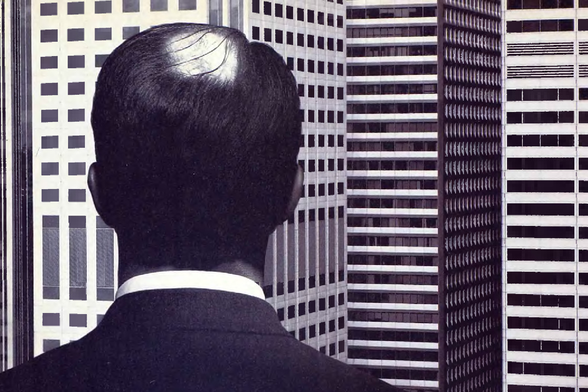 1989 

The back of the head of a man wearing a suit.
He appears to be looking out over a cityscape, possibly from an office building window.
Tags: man, business attire, cityscape, urban setting