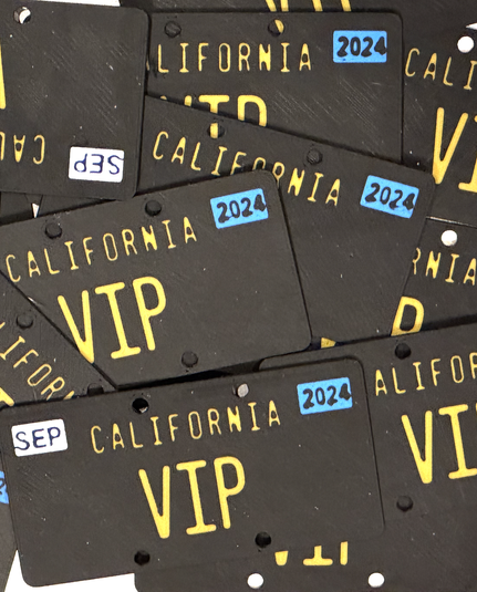 A messy pile of black California license plates that read VIP with white SEP and blue 2024 stickers on them