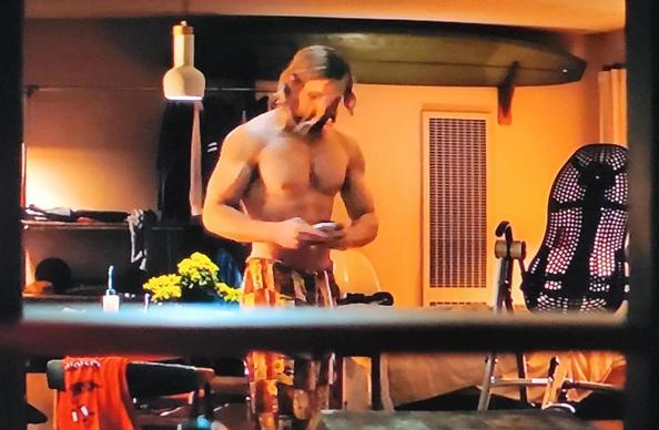 Ryan Gosling barechested looking mighty fine. Washboard abs, beautifully defined titties and arms. He is standing in an apartment. A back teeter totter in the background.
