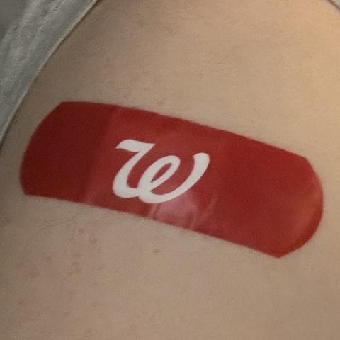 Close-up photo of bright red band-aid with white Walgreens “W” logo on my left shoulder, where I got COVID-19 vaccination.
