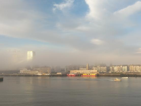 Mist over het centrum en de havengeul van Oostende. Een appartementsgebouw steekt boven de mist uit.