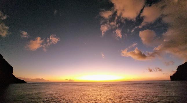 Sonnenuntergang in einer Bucht. Die Sonne versinkt gelb-orange im Wasser. ~~~ Sunset in a bay. The yellow-orange sun sinks into the water.