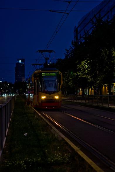 HCP 123N number 2138 in yellow and red colours of Tramwaje Warszawskie, on line 23 direction Nowe Bemowo. Photography made at sunset, the sky in the background is dark blue.