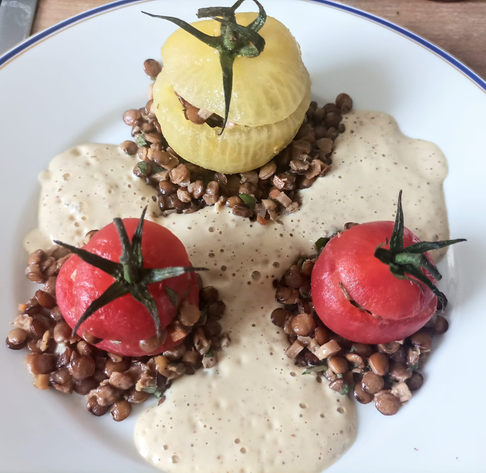 eine größere gelb und zwei kleinere rote Tomaten auf dem Teller mit Linsen und Schaum