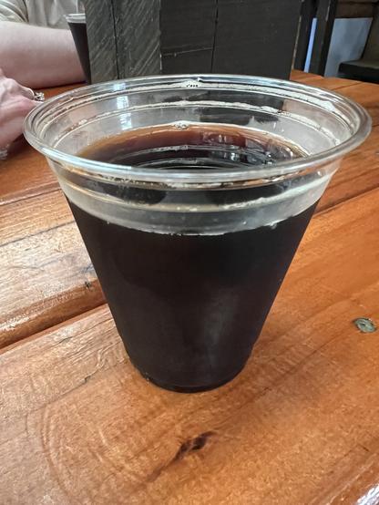 A plastic cup of dark beer - it’s a porter