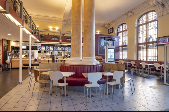 A McDonalds located in a baroque building with fancy columns in the middle of it.