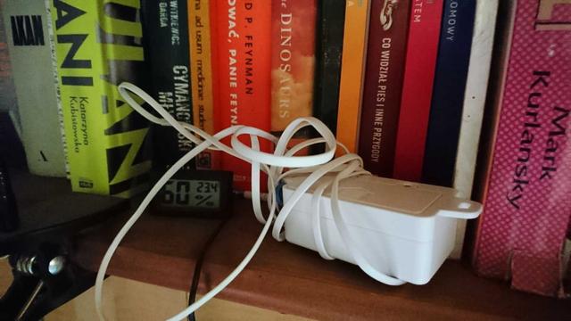 A LoRaWAN sensor next to a simple digital thermometer on a bookshelf