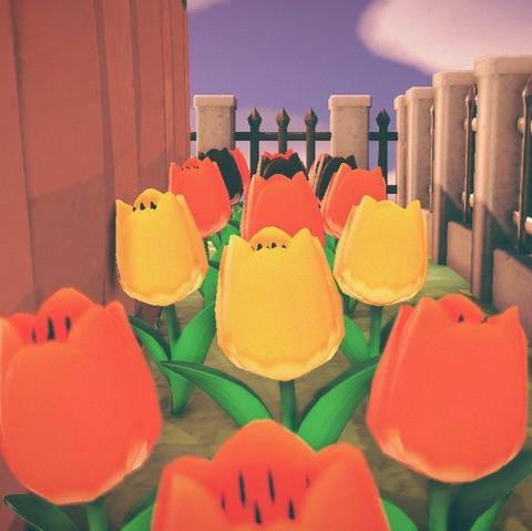 Animal Crossing: New Horizons screenshot. Image shows a narrow row of alternating reddish, yellow, and dark colored tulips with a cliff face to the left and an iron fence to the right and at the far end.