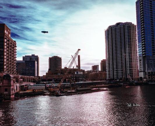 Tinted colour photograph of Wolf point Chicago, construction cranes, and a blimp in the skyline