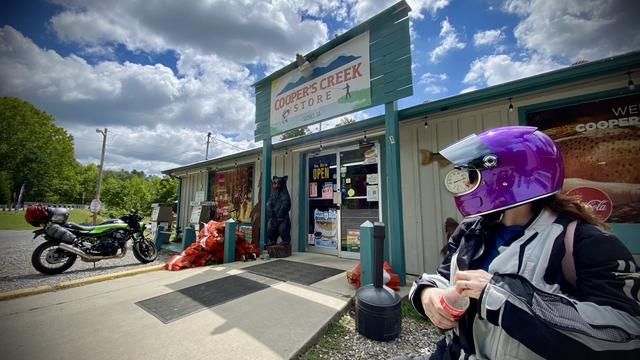 A motorcycle rider in purple helmet taking a rest at the Cooper's Creek Store near Suches GA