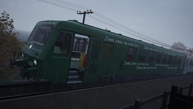 Train Sim World 4 screenshot: DB 628 in green livery that has "♫ HERE COMES THE NIDDY BOI!!!" stamped all over it, on one of the stations along Niddertalbahn, in a rainstorm