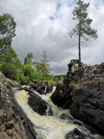 Foto eines Teils der Black Water Falls bei Garve. Der Fluss hat reichlich Wasser und die Kaskaden an Wasser schäumen reichlich, beim in die Tiefe fallen.