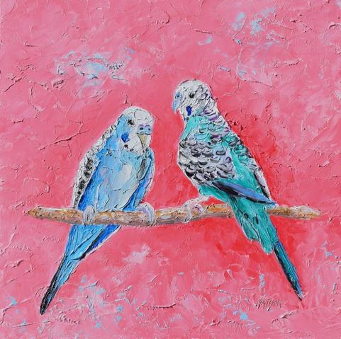 Two vibrant budgerigars, one blue and the other green, are perched side by side on a branch.