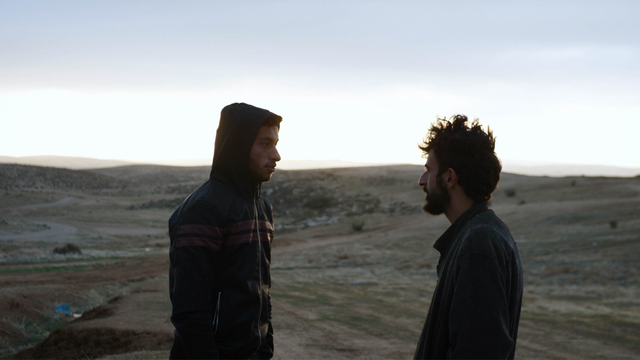 A photograph of two men, nearly silhouetted -- one Palestinian, one Jewish -- facing each other in a desert.