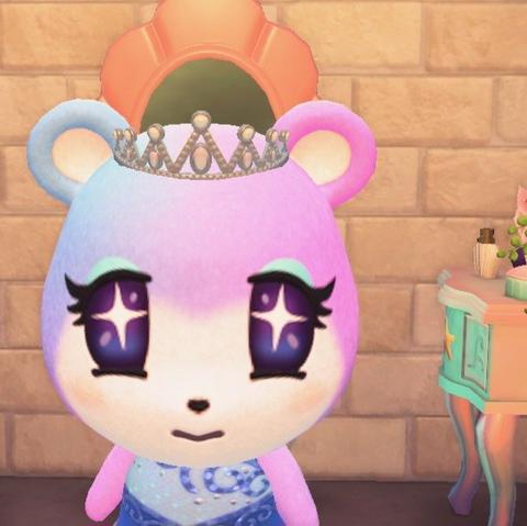 Animal Crossing: New Horizons screenshot. Image shows Judy (blue to purplish bear cub with sparkly eyes) sitting in front of two mermaid vanities with an intense look on her face while wearing a tiara and a blue dress that, not shown, only goes over one shoulder.