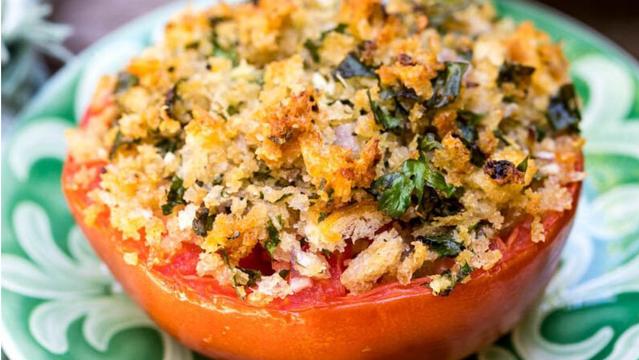 Half a ripe red tomato covered in golden herbed breadcrumbs sits on a small green and white plate. Image from: Vanilla Bean Cuisine