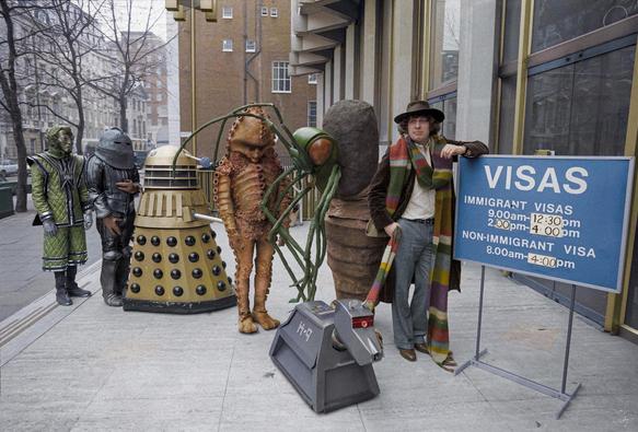 The image shows aliens (from the TV show Dr Who) queuing in the visa line outside the American Embassy in London in February 1978