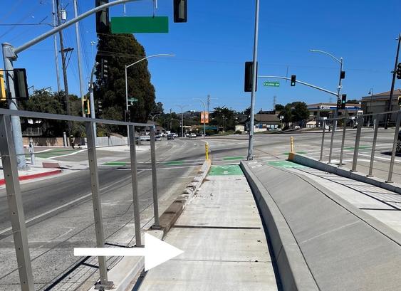 Intersection of North Fremont Street and Casanova Avenue in Monterey. In this photo, shot 8 Sept 2024, a piece of fence that  normally surrounds the bike lanes that were built in the center of the street is missing—apparently yet another motor vehicle has run into this unusual infrastructure. Arrow is pointing to some of the many pieces of sharp debris,  apparently from the collision; the debris in the bike lane stretched nearly to the Ramona intersection.