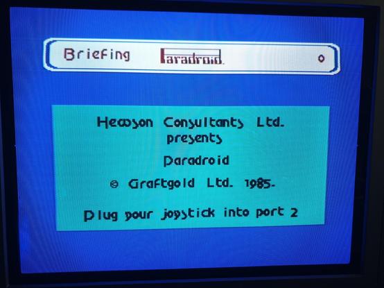 A photo of Paradroid's blue and teal title screen running on a flatscreen CRT TV