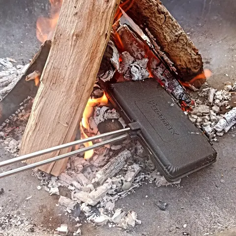 Ein Lagerfeuer, in dem ein gußeisenes Waffeleisen liegt.