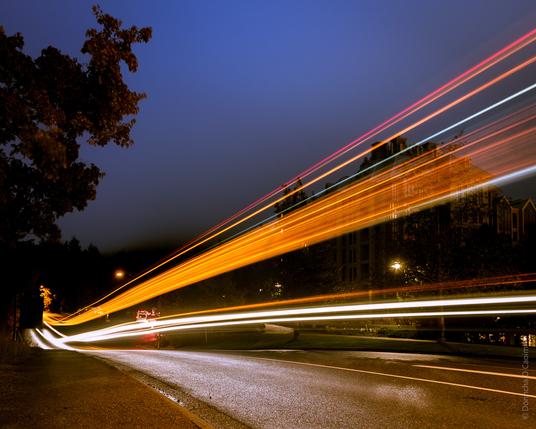 Light from a passing bus is captured on a long exposure photo as it drives by.