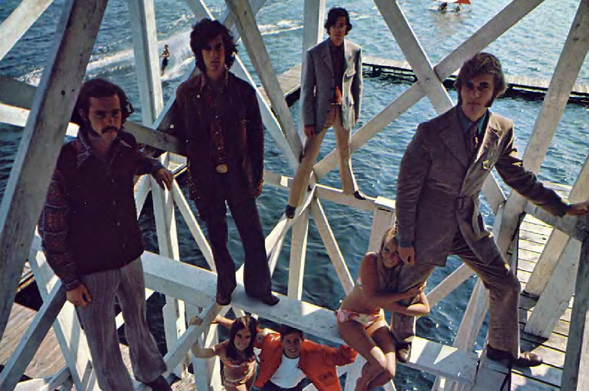 1969
A group of five men in their 20s, dressed in mod and psychedelic styles from the late 1960s, with varying hairstyles including long hair and short hair.
Some have beards or mustaches.
They are posing for a photo on a wooden dock that seems to be floating on water, possibly a boat deck or a pier.
The image is in black and white.
Tags: Beatles, music group, 1960s fashion, mod, psychedelic style, dock, water
