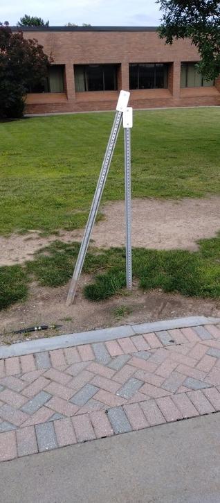Two small rectangular reflectors on sign posts. One of the sign posts is crooked, making it look like one reflector is leaning lovingly on the other.