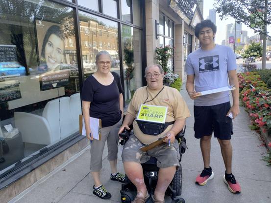 Sheena, Donald, and Luke on a Yonge Street sidewalk, mid-day.