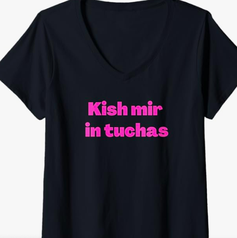 The funny Yiddish saying Kish mir in tuchas is shown in pink lettering on a black V neck T shirt.