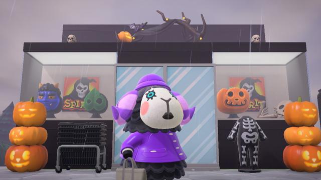 Animal Crossing: New Horizons screenshot taken at an upward angle. Muffy (black sheep with white face and purple striped horns) is walking by a faux building that looks like Spirit Halloween with masks in the windows, a set of baskets outside the door, and skeletons observable from above. Other pumpkin items are also around the store. In the "windows" of the storefront is the Spirit Halloween logo in the windows.