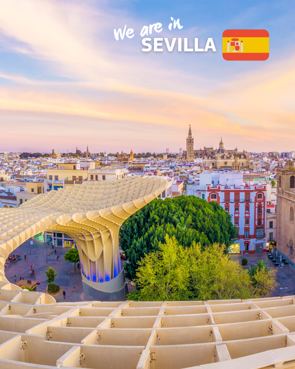 A stunning panorama of Seville, Spain, showcasing the modern wooden structure of Metropol Parasol, also known as 'Las Setas,' in the foreground. The city's historic buildings, including the Cathedral of Seville, can be seen in the background under a colorful sunset sky. The text 'We are in Sevilla' is displayed at the top along with the Spanish flag.