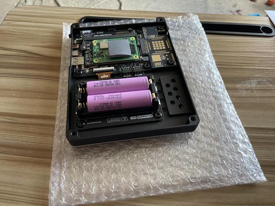 An almost completely assembled console - the batteries (two pink 18650 format cells) & battery carrier are installed. There is a thermal pad attached to the compute module board.