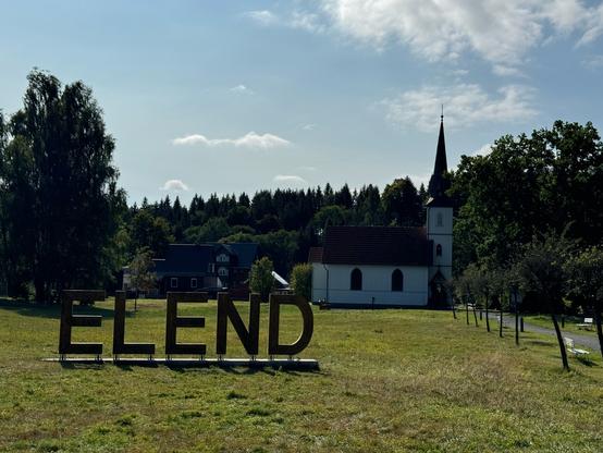 Wiese, kleine Holzkirche, Schriftzug: Elend