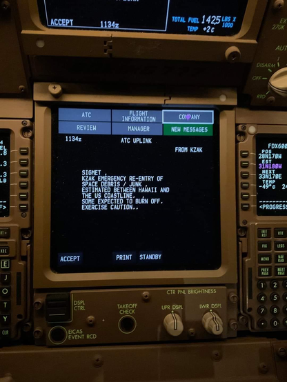 Photograph shows part of an airplane flight deck, centred on a console screen which reads “Sigmet Significant Meteorological Event]: Emergency re-entry of space debris / junk estimated between Hawaii and the US coastline. Some expected to burn off. Exercise caution.” Another screen is partially visible, showing a partial callsign beginning with “FDX”, indicating this is a FedEx aircraft.