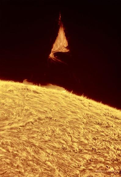 A triangular solar prominence hovers over the Sun's surface.