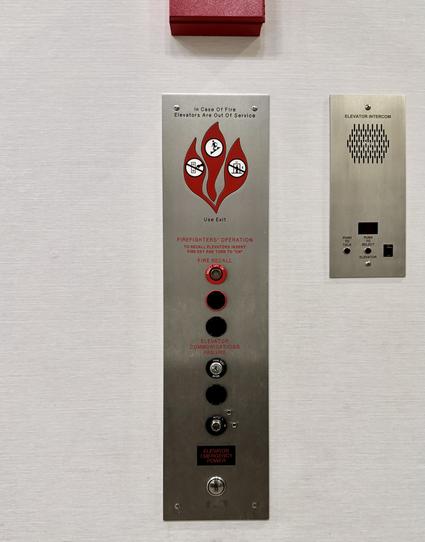 An elevator call panel has 8 different indicators, switches, keyholes and buttons on it plus lots of instructions about what to do in case of fire. The one button to actually call the elevator isn't labeled.