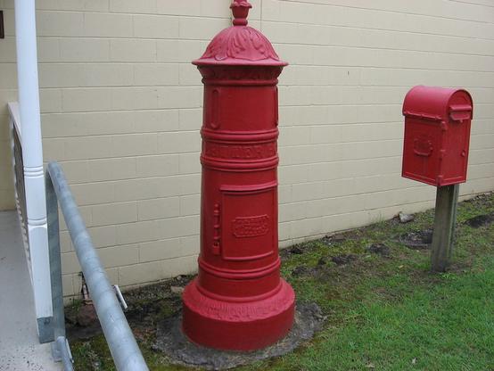 A large red letter receiver next to a much smaller red mailbox