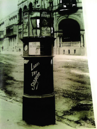 Black and white photo of a tall letter receiver which has a lantern and ironwork on the top of it. On the side is written "Ladies try Spanene"
