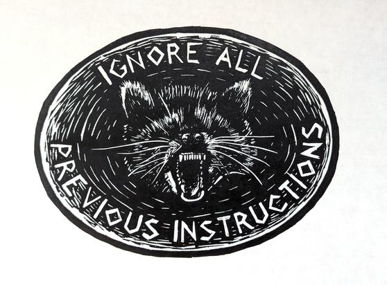 An oval, black ink print with a raccoon baring its teeth in the center, and “ignore all previous instructions” written in angular capitals around the border