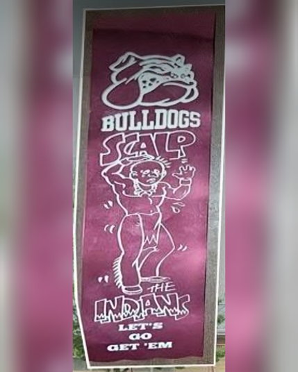 A burgundy ribbon with white lettering shows a bulldog scalping a caricature of a Native. Text reads: Bulldogs scalp the Indians Let's go get 'em