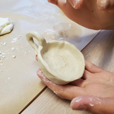 A hand holding a clay sculpted candlestick holder
