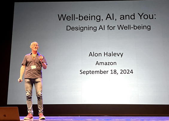 Alon Halevy standing on the big stage of Semantics 2024 in front of his openiing slide. The title says: Well-being, AI and You - Designing AI for QWell-Being.