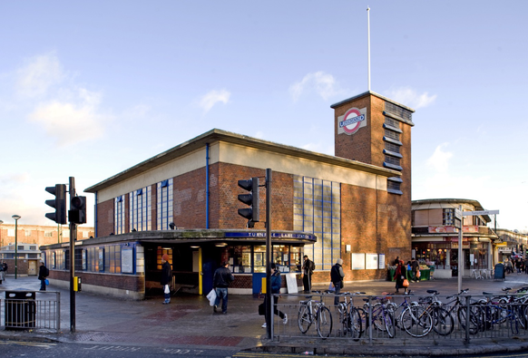A colour photograph of Turnpike Lane tube station with its curved entrance porch and brick ventilation tower
