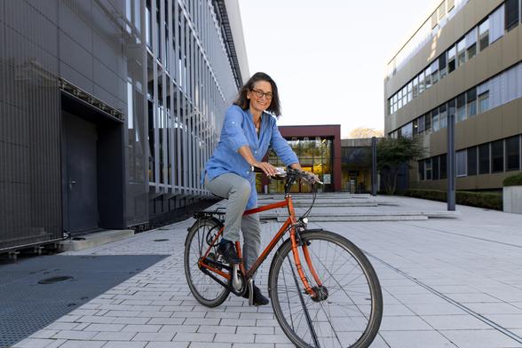 Wissenschaftlerin Ulrike Niemeier auf einem roten Fahrrad vor dem Gebäude des deutschen Klimarechenzentrums (DKRZ) in Hamburg.