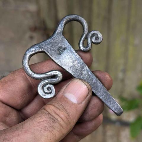 la boucle de face avec le poinçon du forgeron, une barre avec deux volutes, une de chaque coté.