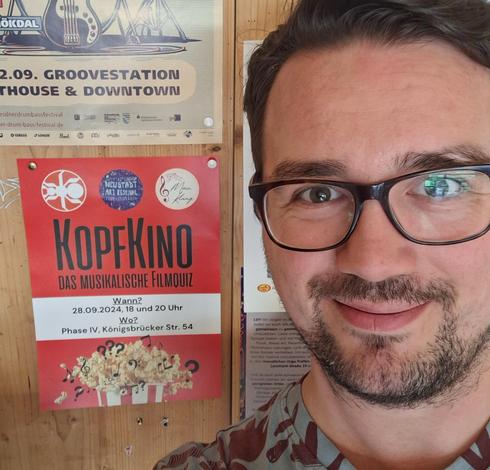 Manuel vor einem Plakat des Programms KopfKino.