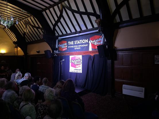 The background of the stage in a pub function room. Banner is for the Outside the Box Comedy Club