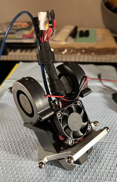 The FLSun hot end effector housing with two larger 5025 direct blower fans installed on each side along with new fan ducts on the bottom meant to better direct air to the part as it’s being printed.